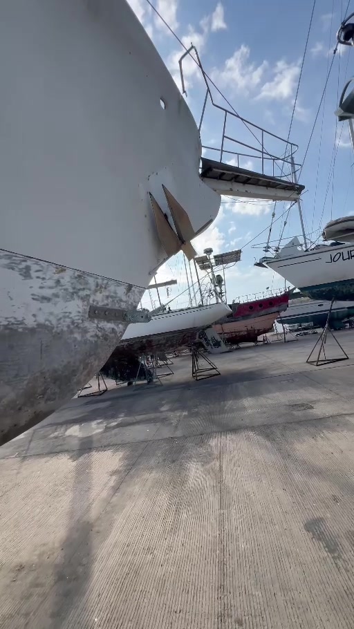 Low-angle view of the end of Tortuga’s hull and a projecting platform with railings, with other boats beyond.